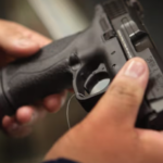 Primer plano de unas manos que manipulan una pistola.