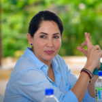 Luisa González sentada a una mesa durante una reunión.