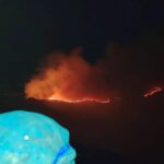 Llamas y humo de un incendio forestal durante la noche.