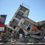 Edificio inclinado y estructuras dañadas junto a una calle.