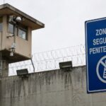 Torre de vigilancia y señal de prohibición de teléfonos en una zona penitenciaria.