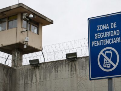 Torre de vigilancia y señal de prohibición de teléfonos en una zona penitenciaria.