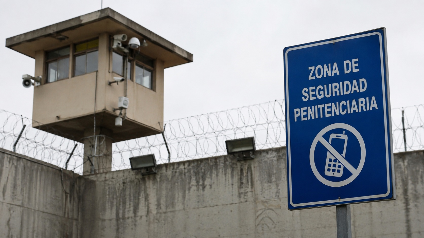 Torre de vigilancia y señal de prohibición de teléfonos en una zona penitenciaria.