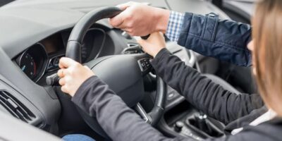 Instructor acompaña a una persona que practica la conducción de un vehículo.