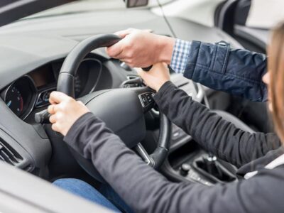 Instructor acompaña a una persona que practica la conducción de un vehículo.