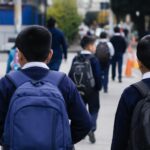 Estudiantes con mochilas caminan hacia un establecimiento educativo.