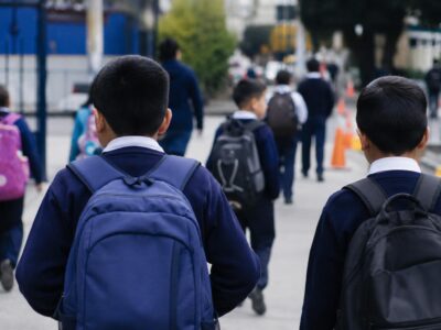 Estudiantes con mochilas caminan hacia un establecimiento educativo.