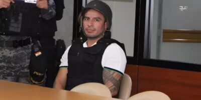 Daniel Salcedo sentado junto a un agente uniformado en una sala.