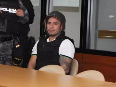 Daniel Salcedo sentado junto a un agente uniformado en una sala.