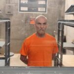 Hombre con uniforme naranja dentro de un recinto penitenciario.