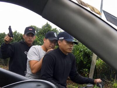 Hombre acompañado por agentes durante un procedimiento junto a un vehículo.