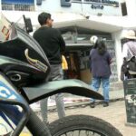 Motocicleta policial junto a personas y un vehículo de atención de emergencias.