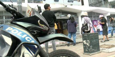 Motocicleta policial junto a personas y un vehículo de atención de emergencias.