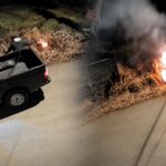 Captura nocturna con un vehículo estacionado y fuego en un área de vegetación.
