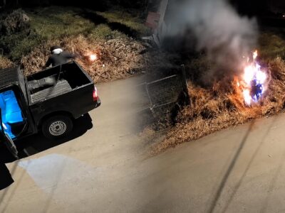 Captura nocturna con un vehículo estacionado y fuego en un área de vegetación.