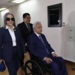 Lenín Moreno en silla de ruedas acompañado por personas en un edificio.