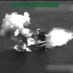 Captura aérea en blanco y negro de una embarcación envuelta en humo y llamas.