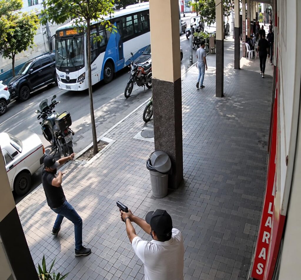 Captura de cámara de seguridad de personas en una acera junto a una calle.