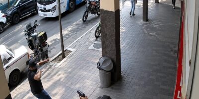 Captura de cámara de seguridad de personas en una acera junto a una calle.