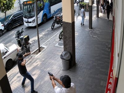 Captura de cámara de seguridad de personas en una acera junto a una calle.