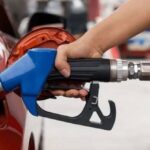 Una persona introduce un surtidor de combustible en el depósito de un vehículo.