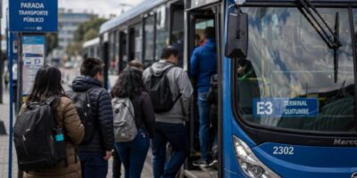 Pasajeros suben a un autobús azul en una parada de transporte público.