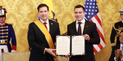 Daniel Noboa y Marco Rubio posan con un documento frente a las banderas de Ecuador y Estados Unidos.