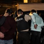 Agentes de Policía junto a dos hombres con las manos detrás de la espalda durante un operativo nocturno.