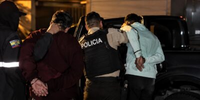 Agentes de Policía junto a dos hombres con las manos detrás de la espalda durante un operativo nocturno.