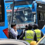 Agentes municipales y otras personas junto a la puerta de un autobús azul.