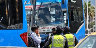 Agentes municipales y otras personas junto a la puerta de un autobús azul.