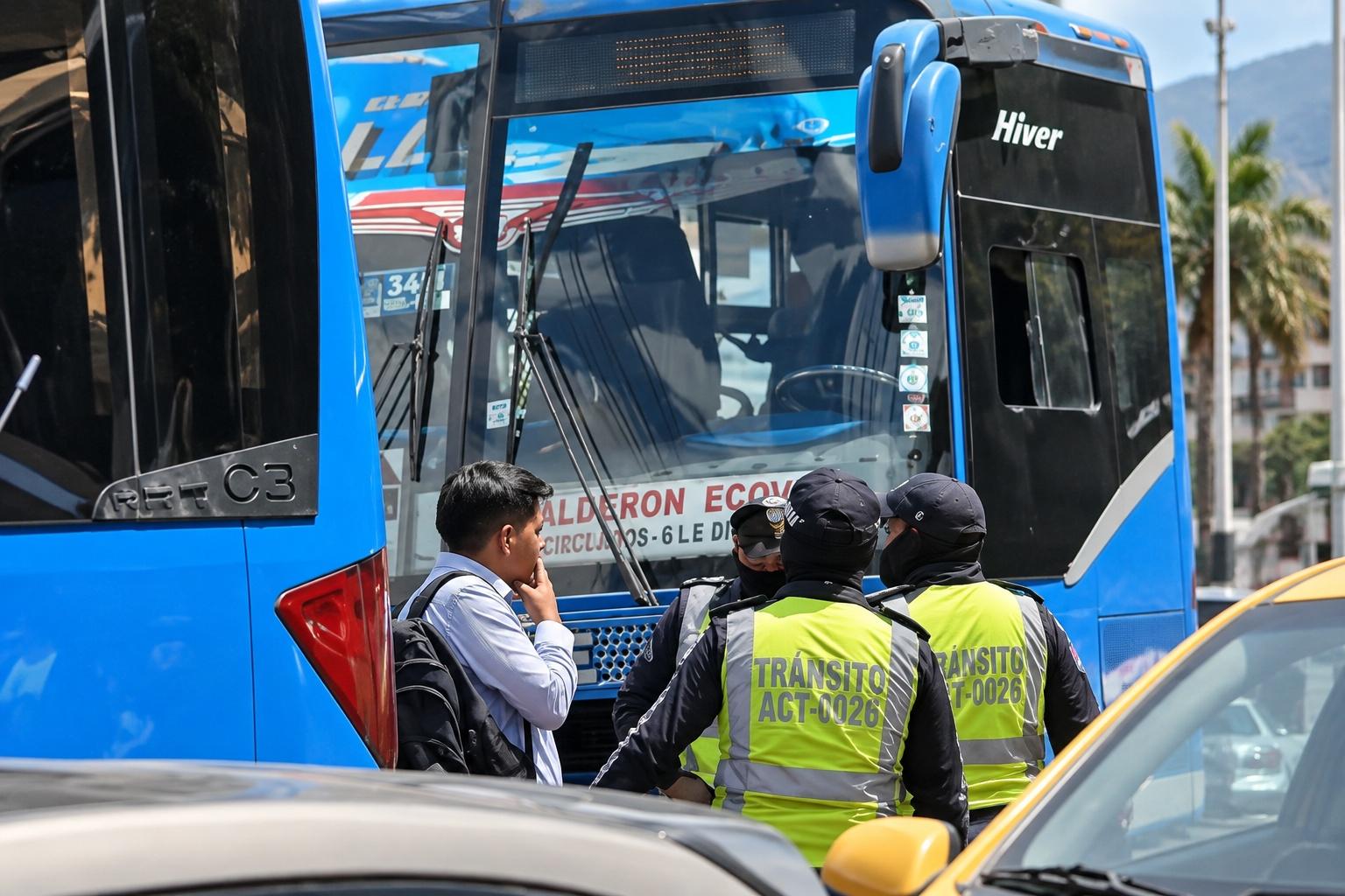 Agentes municipales y otras personas junto a la puerta de un autobús azul.
