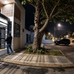 Entrada de una urbanización y una acera iluminadas durante la noche.