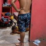 Captura de video de un hombre de pie y un menor con el rostro difuminado en el interior de una vivienda.
