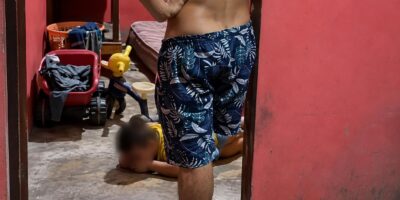 Captura de video de un hombre de pie y un menor con el rostro difuminado en el interior de una vivienda.