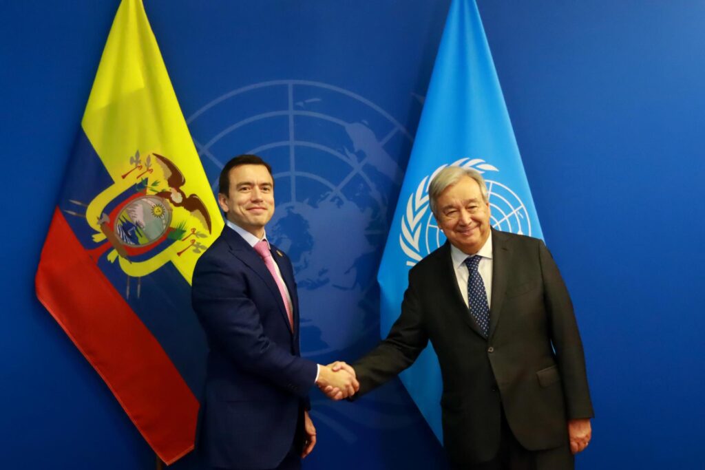 Daniel Noboa y António Guterres se estrechan la mano frente a banderas de Ecuador y Naciones Unidas.