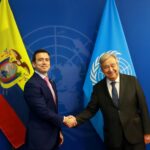 Daniel Noboa y António Guterres se estrechan la mano frente a banderas de Ecuador y Naciones Unidas.
