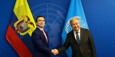 Daniel Noboa y António Guterres se estrechan la mano frente a banderas de Ecuador y Naciones Unidas.
