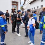 Trabajadores de limpieza, agentes y otros ciudadanos reunidos en una calle.