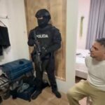 Agentes de Policía junto a un hombre sentado en el interior de una habitación.