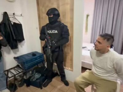 Agentes de Policía junto a un hombre sentado en el interior de una habitación.