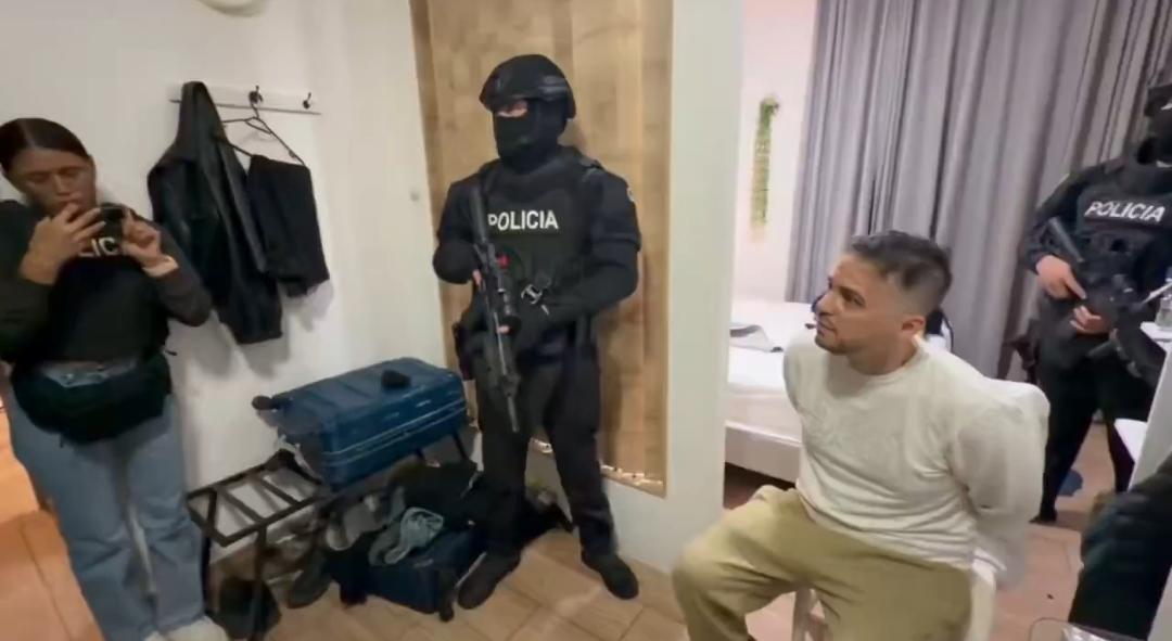Agentes de Policía junto a un hombre sentado en el interior de una habitación.