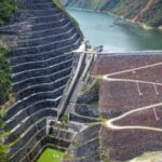 Vista aérea de una represa y un embalse rodeados de montañas.