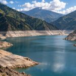 Un embalse entre montañas, con una amplia franja de terreno expuesto junto al agua.