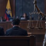 Imagen ilustrativa de una estatua de la Justicia con una balanza, frente a una sala judicial.