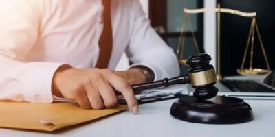 Imagen ilustrativa de una persona ante documentos, un mazo judicial y una balanza.