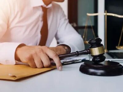 Imagen ilustrativa de una persona ante documentos, un mazo judicial y una balanza.