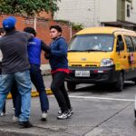 Dos hombres y un agente de tránsito en una calle con vehículos.