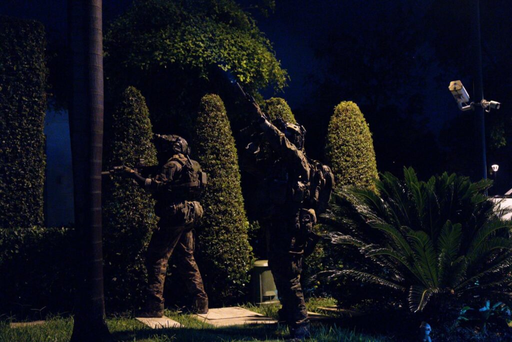Militares equipados con cascos durante un operativo nocturno en una zona con vegetación.