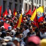 Una multitud con banderas rojas y de Ecuador durante una movilización en la calle.